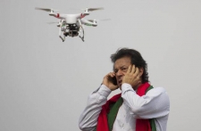 Pakistan's cricketer-turned-politician Imran Khan talks over a phone as a camera-equipped drone hovers outside a parliament in Islamabad on Thursday.